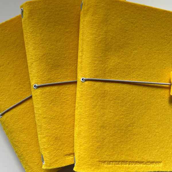 3 bright yellow journals stacked on top of each other