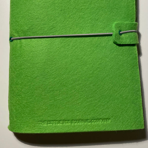 Bright green A5 felt wrap journal showing elastic strap and embossed logo
