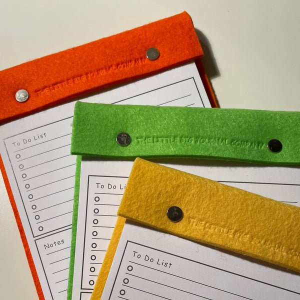 Bright orange, lime green, vivid yellow To do list note pads fanned out to show range