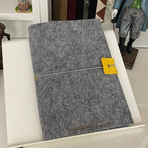 Sliver grey A5 felt wrap notebook shown on desk for men in study