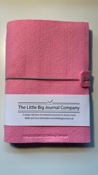 Pink felt wrap A5 refillable journal with elastic strap holding notebooks inside with packaging description