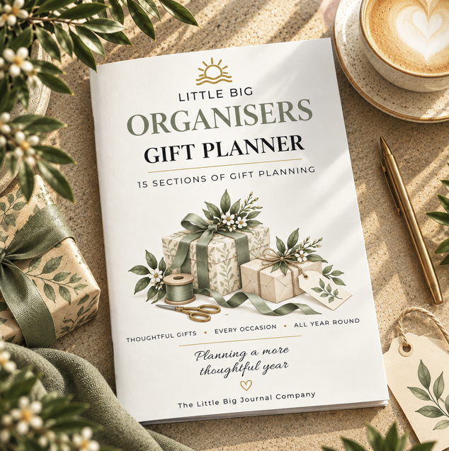 A gift planner insert titled 'Little Big Organisers Gift Planner' lies on a beige textured surface surrounded by styled props including wrapped gift boxes, greenery, a coffee cup, a pen, and a tag. The planner cover is white with green and black text and an illustration of wrapped presents with ribbons.