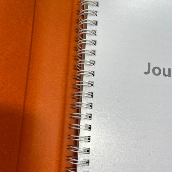 burnt orange faux leather refillable journal showing a close up of the spiral bound lined paper insert.