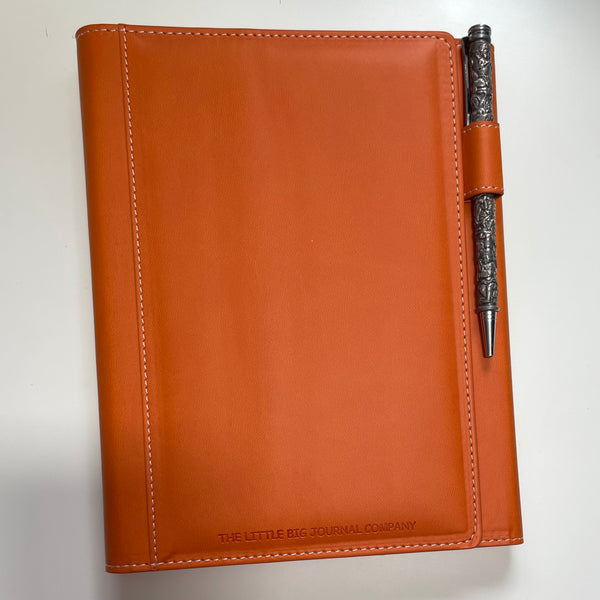 burnt orange faux leather refillable journal showing a close up of the pen holder which is located on the front side of the journal